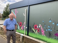Cllr Bill Handley outside the Northstowe temporary community centre. The side of the temporary community centre features artwork, inspired by nature and designed with input from residents.
