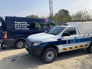 A blue van that contains wording on the side saying 'Supporting and investing in our local communities' along with a South Cambridgeshire District Council pick-up truck.